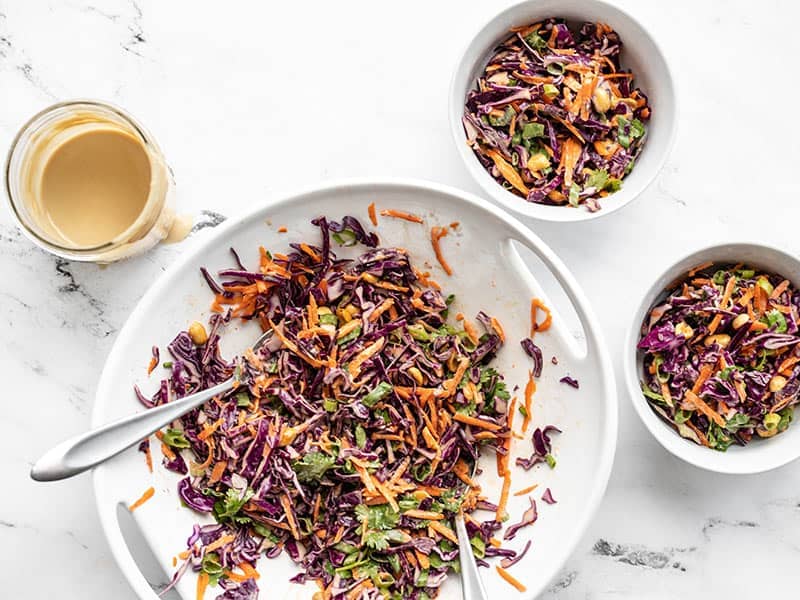 Crunchy cabbage salad coated in dressing, dished out to two bowls.