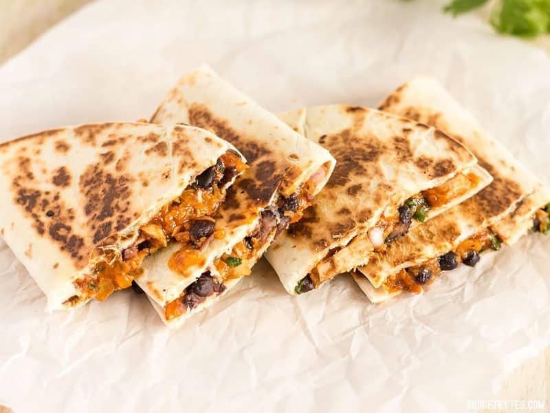 Stacked Ultimate BBQ Chicken Quesadillas on parchment paper