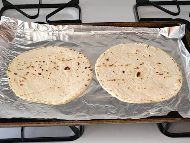 pre-bake tortillas - two tortillas on baking sheet lined with tin foil 