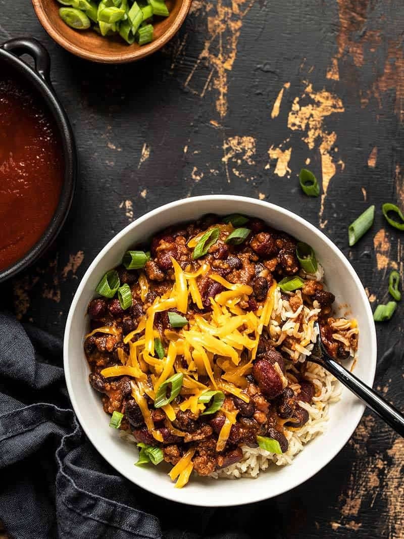 Finished bowl of BBQ Beef and Beans served over rice and topped with cheddar and green onions.