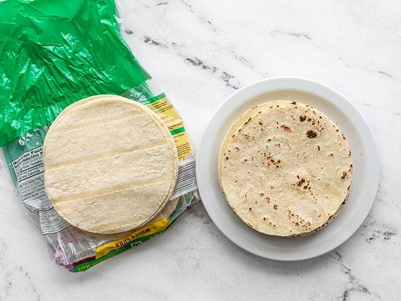 two stacks of corn tortillas, one toasted, one untoasted