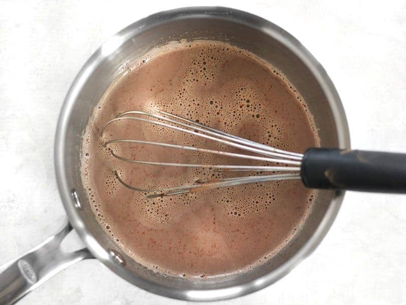 Spices whisked into hot milk in the sauce pot