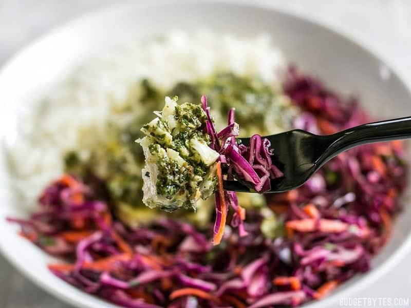 Close up of a forkful of baked chimichurri fish and slaw