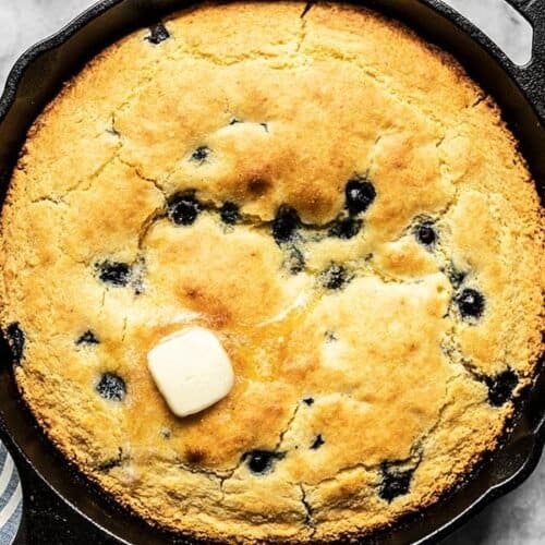 Close up of baked Lemon Blueberry Cornbread in the skillet with some butter melting on top.