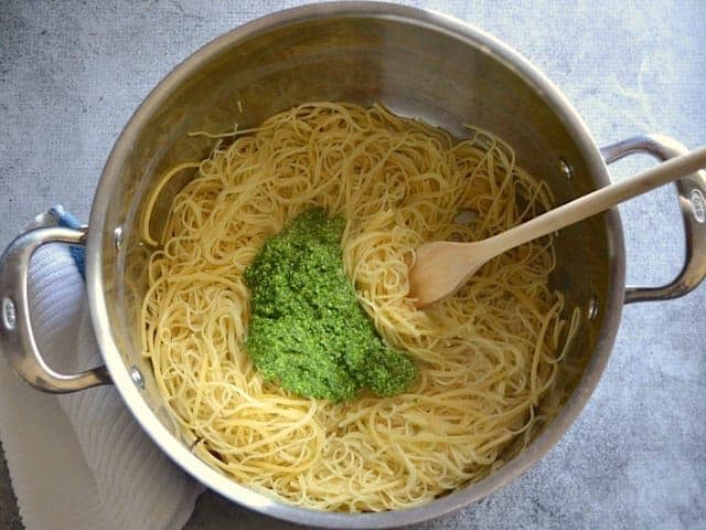 Pesto added to cooked pasta in the pot