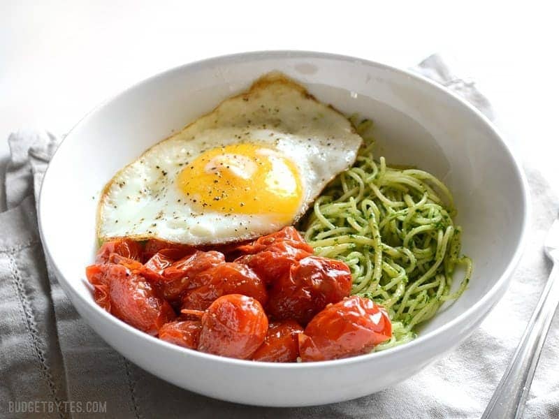 Side view of the bowl of parsley pesto pasta with tomatoes and fried egg