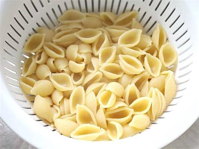 Cooked pasta draining in a white colander