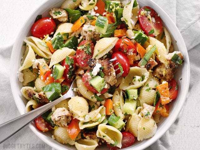 A forkful of Greek Chicken Pasta Salad resting on top of the bowl